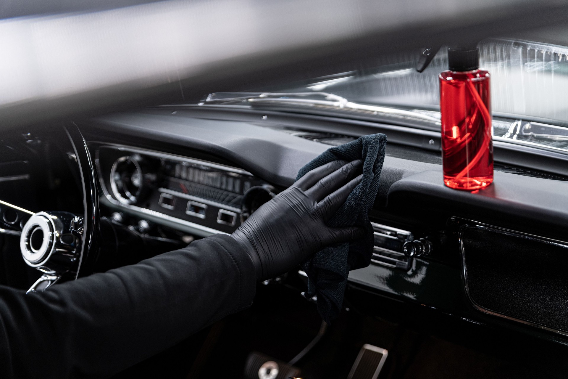 Employee of a car wash or a car detailing studio cleans the cockpit